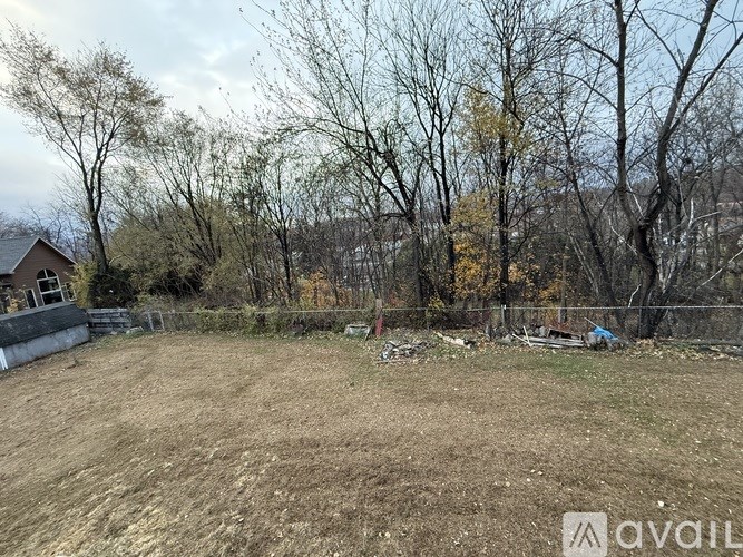 A field with trees and a house in the background.