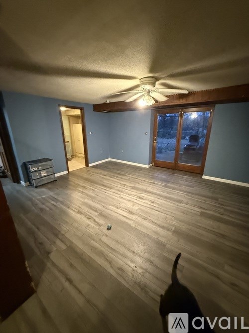 A room with a ceiling fan and wooden flooring.