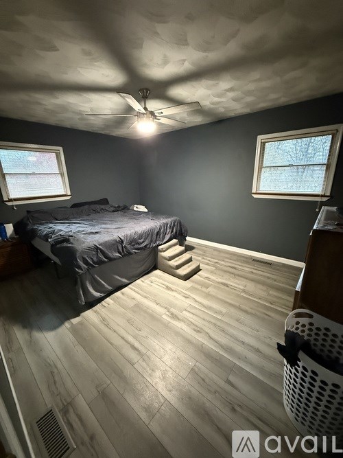 A bedroom with a bed, a window, and a ceiling fan.