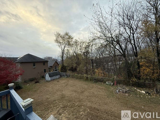 A backyard with a house, trees, and a fence.