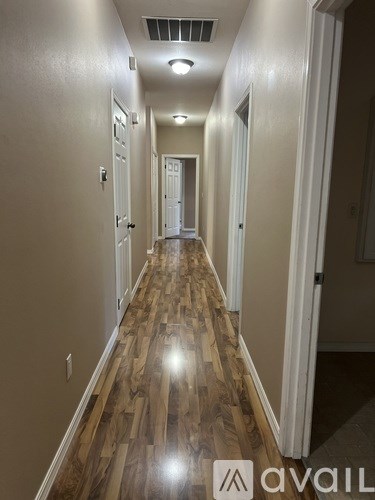 A long hallway with wood floors and white walls.