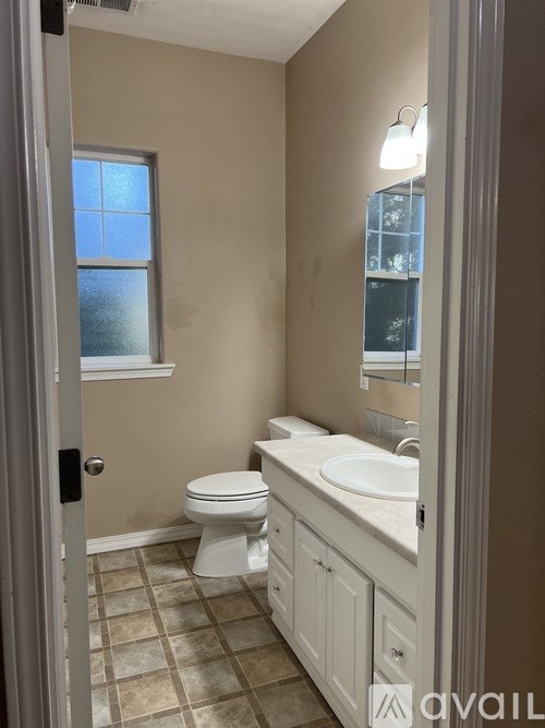 A bathroom with a toilet, sink, and a window.