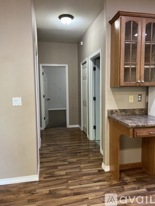 A hallway with wood floors and a counter with a backsplash.
