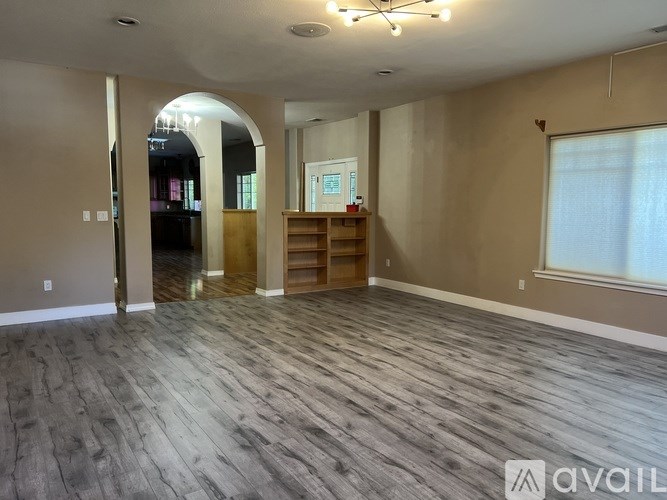 A spacious room with wood flooring and a large window.