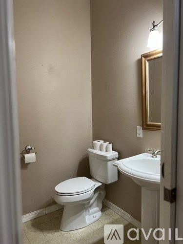 A bathroom with a toilet, sink, and mirror.