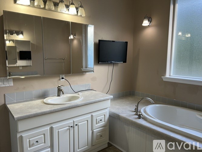 A bathroom with a sink, mirror, and bathtub.