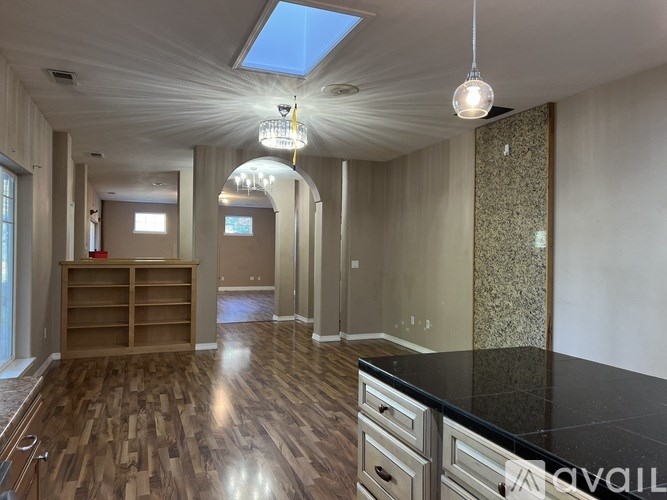 A spacious kitchen with wooden floors and a skylight.