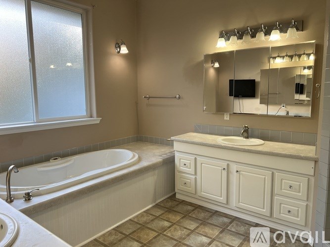 A bathroom with a tub, sink, and mirror.