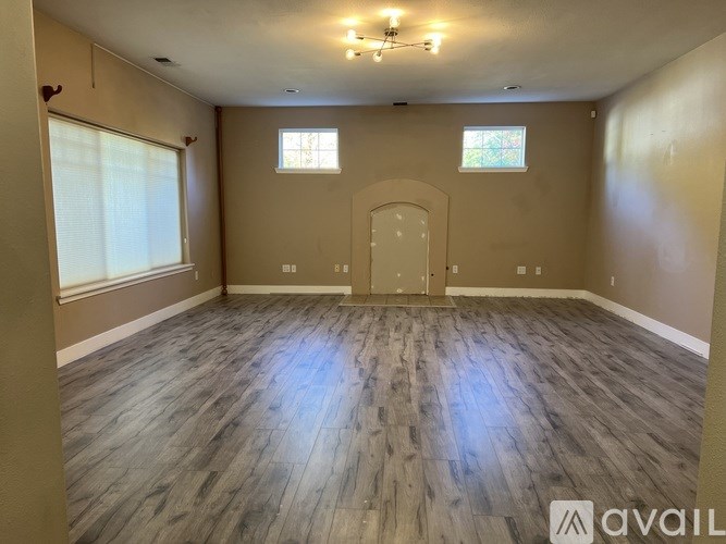 A room with wooden flooring and a large arched doorway.