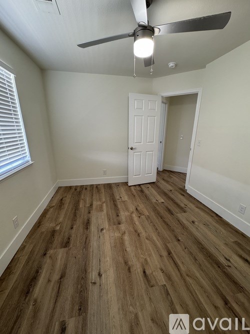 A room with a ceiling fan and wooden flooring.