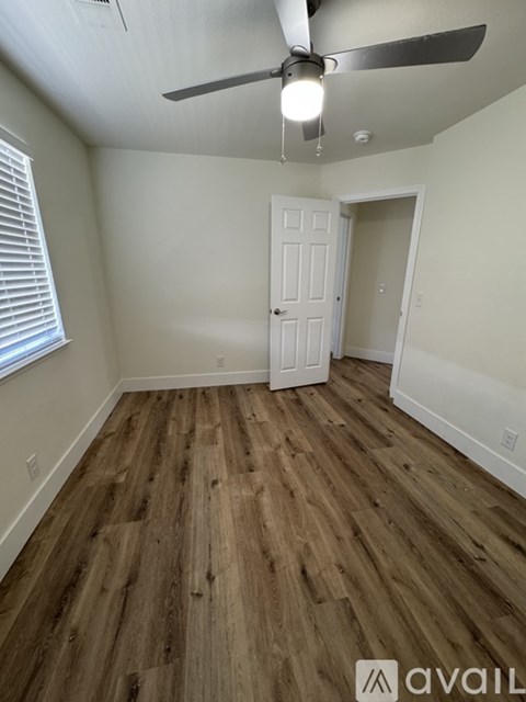 A room with a ceiling fan and wooden flooring.