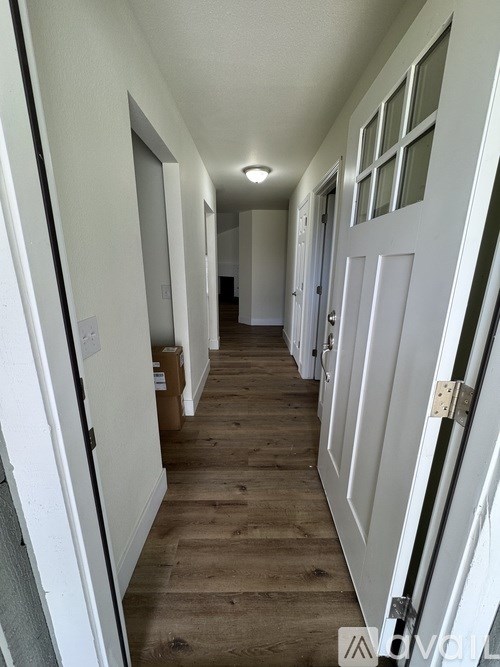 A long hallway with white doors and a brown box on the floor.