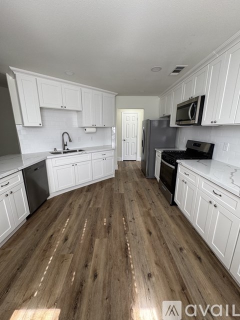 A kitchen with white cabinets and wooden floors.