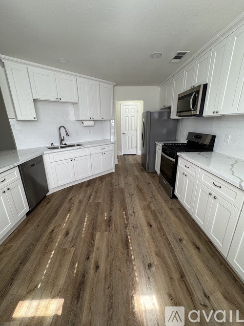 A kitchen with wooden floors and white cabinets.