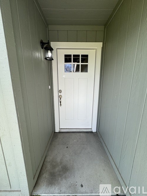 A white door with a glass window is set in a white wall.