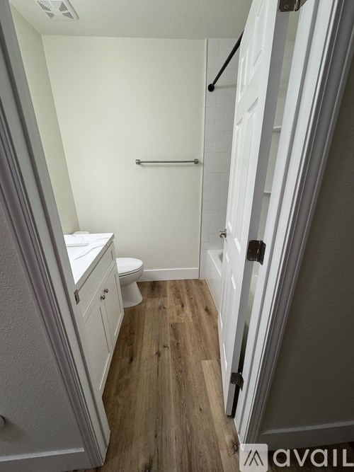 A bathroom with a toilet, sink, and wooden floor.