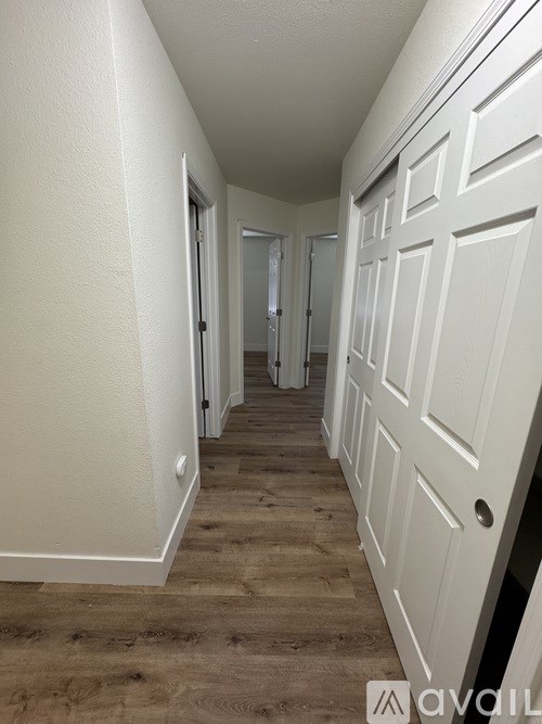 A long hallway with white doors and wooden floors.