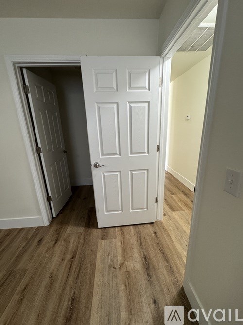 A white door is in a room with wooden floors.