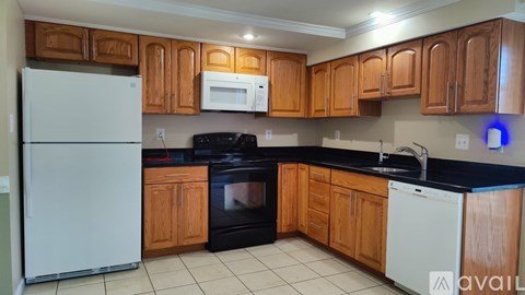 A kitchen with wooden cabinets and black countertops.