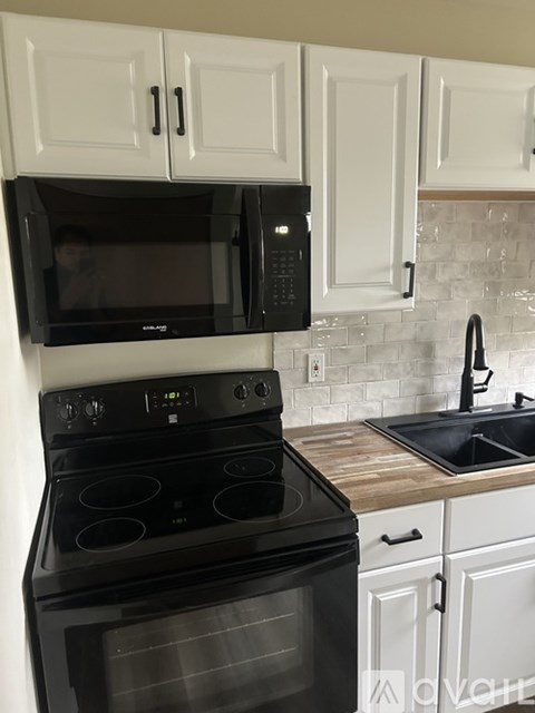 A black stove top oven sits under a microwave in a kitchen.