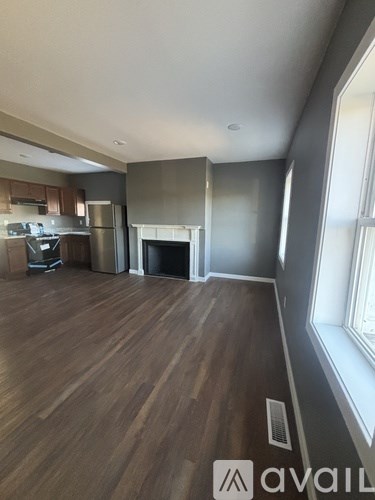 A living room with a fireplace and a kitchen area in the background.