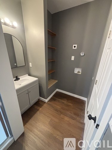 A bathroom with a sink, mirror, and wooden floors.