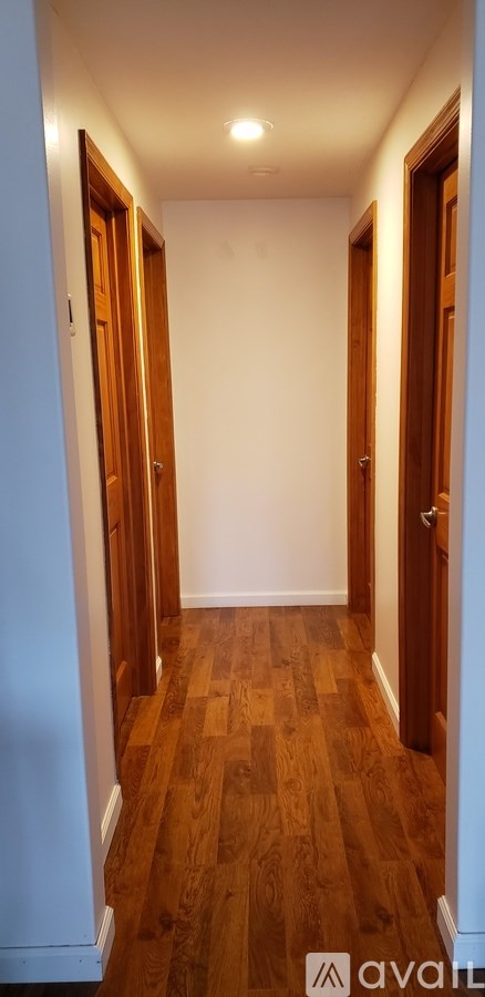 A long hallway with wooden floors and white walls.