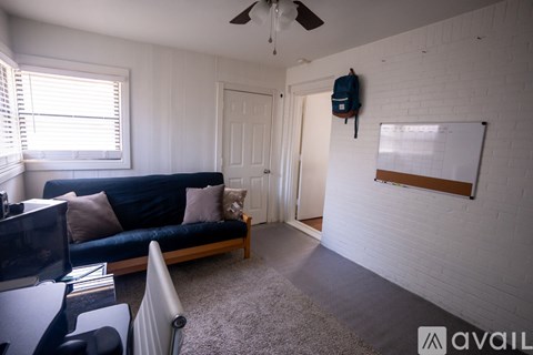 A living room with a blue couch and a white brick wall.