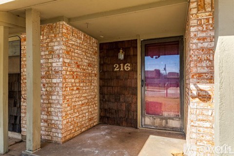 A red brick wall with a doorway leading to a balcony.