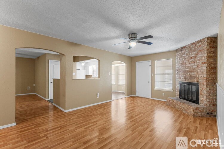 A spacious room with a fireplace and a ceiling fan.