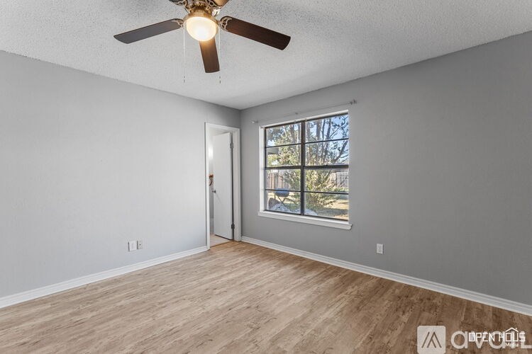 A room with a ceiling fan and a door leading to a balcony.