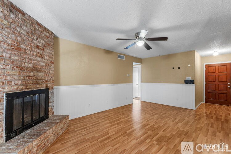 A room with a brick fireplace and wooden floors.