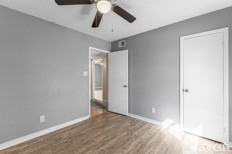 A room with a ceiling fan and two doors.