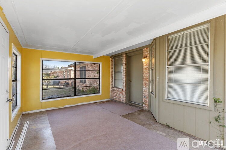 A room with yellow walls and a large window with a view of a backyard.