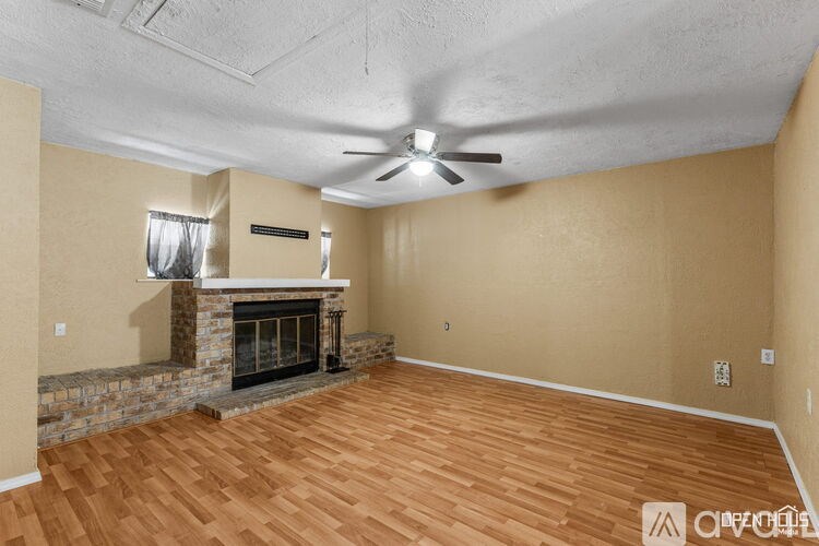 A living room with a stone fireplace and wood flooring.