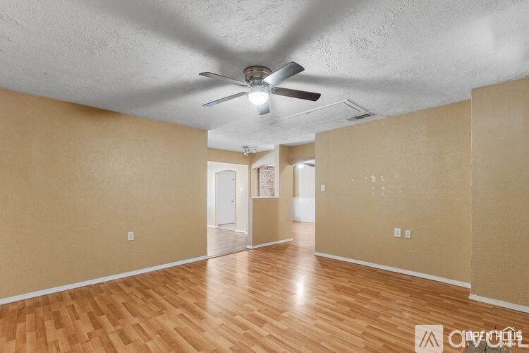 Empty room with a ceiling fan and wooden flooring.