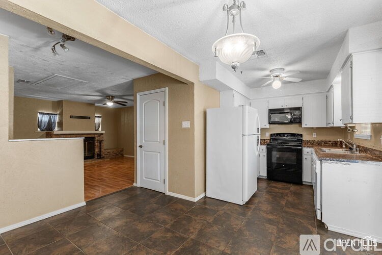 A kitchen with white appliances and brown flooring.