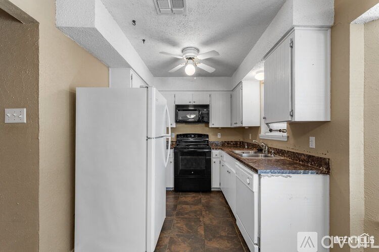A kitchen with white appliances and brown floors.