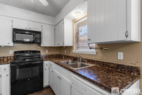 A kitchen with white cabinets and a black stove top oven.