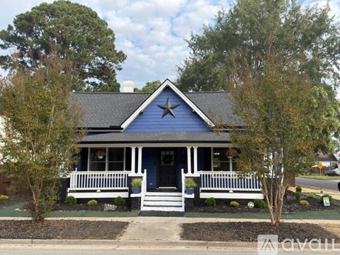 A blue house with a white porch and a star on the roof.