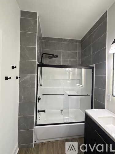 A modern bathroom with a glass shower enclosure and a white sink.