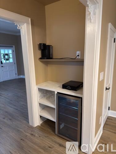 A kitchen pantry with a white door and a black coffee maker on a shelf.