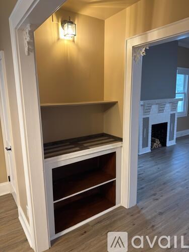 A white cabinet with glass doors and shelves is in a room with wooden flooring.