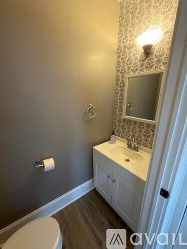 A bathroom with a toilet, sink, and mirror.