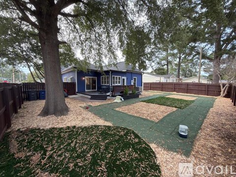 A backyard with a blue house, a baseball diamond, and a tree.