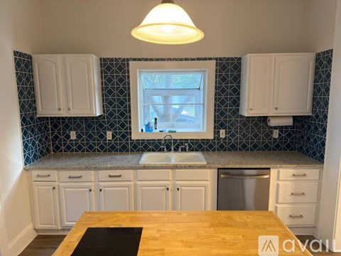 A kitchen with white cabinets and a window.