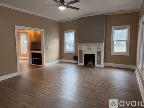 A spacious room with a fireplace and a ceiling fan.