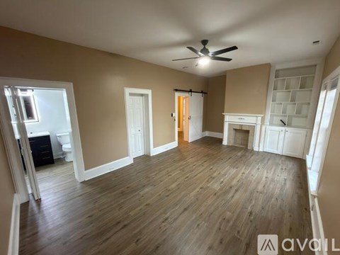 A spacious room with wooden flooring and a ceiling fan.