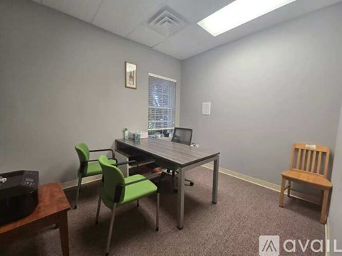 A room with a desk, chairs, and a printer.