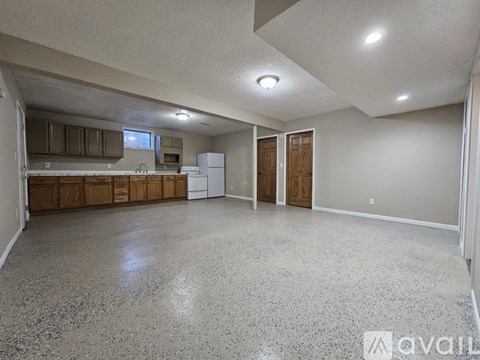 A spacious room with a kitchen area and a refrigerator.